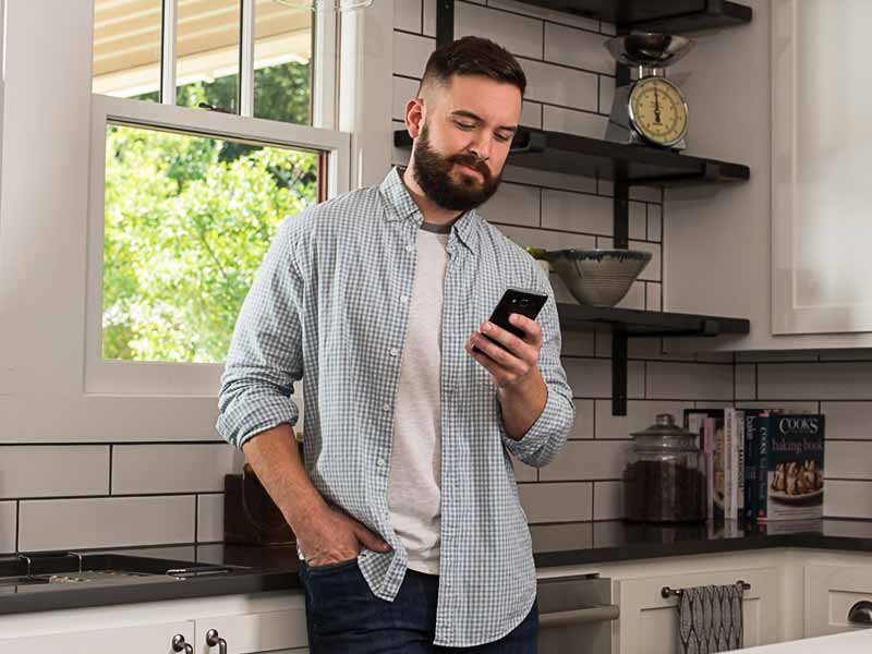 Man in kitchen looking at phone